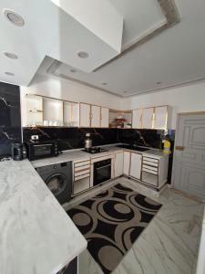 a kitchen with white cabinets and a black and white rug at Omaima villa in Taguermess
