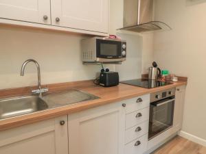 a kitchen with a sink and a microwave at The Cider Press, Motcombe, Shaftesbury in Motcombe