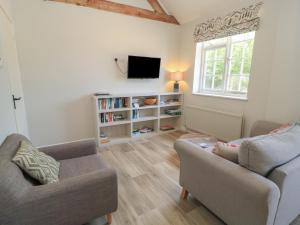 a living room with two chairs and a tv at The Cider Press, Motcombe, Shaftesbury in Motcombe