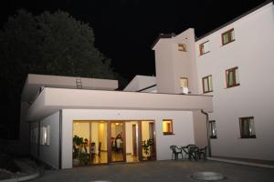 a large white building at night with people standing outside at Guest House Ostojić in Međugorje