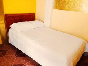 a white bed in a room with a yellow wall at 1 BR Room 1 floor Cusco in Cusco