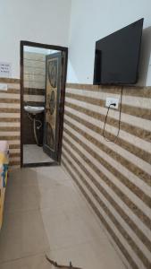 a bathroom with a toilet and a television on a wall at Hotel New Aroma inn in Tājganj