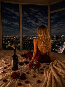 a woman sitting on a bed with two glasses of wine at Luxury 3-Beds Apartment in Yorkville with the Best City View in Downtown Toronto in Toronto