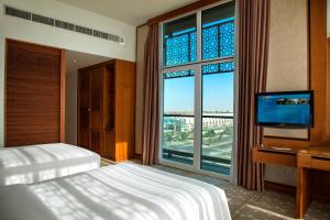 a bedroom with a bed and a tv and a large window at Yas Island Rotana Abu Dhabi in Abu Dhabi