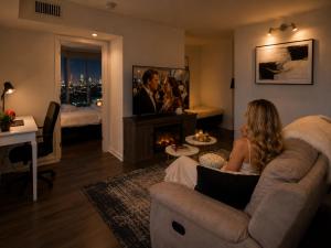 a woman sitting on a couch in a living room with a tv at Luxury 3-Beds Apartment in Yorkville with the Best City View in Downtown Toronto in Toronto