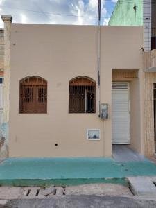 a white building with two windows and a door at Seis Quarto Hospedaria - Suíte Com Ar ou Ventilador - Self Checkin - Centro in Juazeiro do Norte