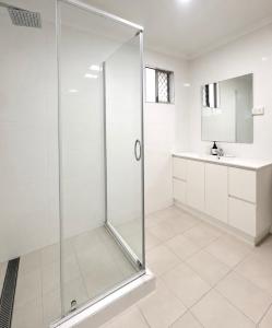 a white bathroom with a shower and a sink at 'The Station House' Mount Isa in Mount Isa