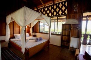 a bedroom with a canopy bed in a room with windows at Cabinas Jenny Cahuita in Cahuita