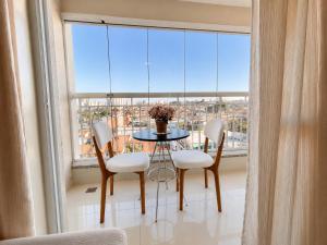 a table and chairs in a room with a large window at Luxury Studio - Próx Aeroporto GRU - Com Ar Condicionado in Guarulhos