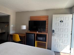 a bedroom with a bed and a television and a desk at Days Inn & Suites by Wyndham Needles in Needles