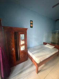 a bedroom with a bed and a wooden cabinet at Amed beach homestay in Ambat +6 photos