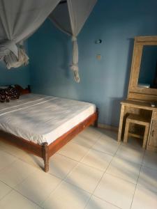 a bed in a room with a blue wall at Amed beach homestay in Ambat