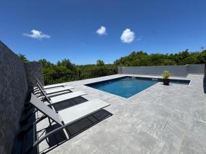 a swimming pool with lounge chairs on a patio at Bas de villa in Grand-Bourg