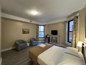 a bedroom with a bed and two chairs and a television at Bauer Guesthouse in Toronto