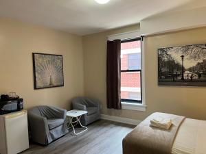 a bedroom with a bed and two chairs and a window at Bauer Guesthouse in Toronto