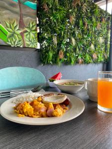 a plate of food with rice and sausage and a glass of orange juice at Hotel Doral Inn in Ibagué