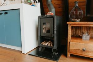 a wood stove in a room next to a refrigerator at Cabana Veneza in Santa Teresa