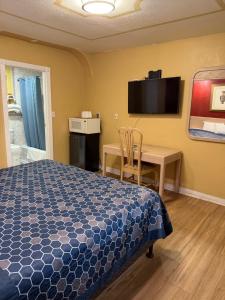 a bedroom with a bed and a desk and a tv at Penguin Motel in Harbor City