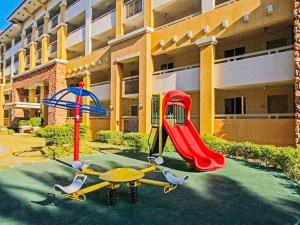 a playground with a slide and an umbrella in front of a building at 2BR Condo with pool at Sorrento Oasis Pasig in Manila
