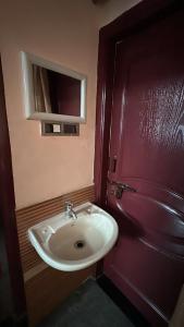 a bathroom with a white sink and a red door at Sri Devi Krupa in Hubli