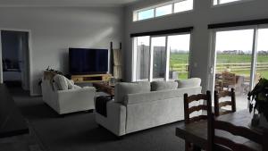 a living room with two couches and a flat screen tv at The Quiet Paddock in Kairanga