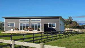 a gray house with a wooden fence in front of it at The Quiet Paddock in Kairanga