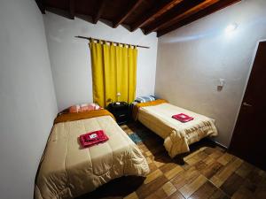 a bedroom with two beds and a yellow curtain at Salvita Hospedaje y Excursiones in El Peñón