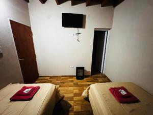 a room with two beds and a flat screen tv at Salvita Hospedaje y Excursiones in El Peñón +2 photos