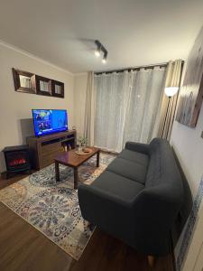 a living room with a black couch and a tv at Hermoso depto. con estacionamiento in Los Ángeles