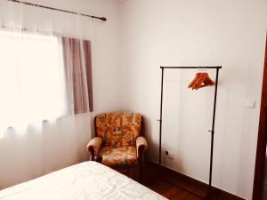 a bedroom with a chair and a bed at Casa de Cima in Doze Ribeiras