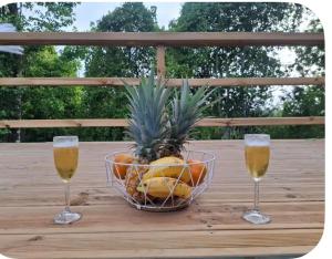 two glasses of champagne and a bowl of fruit on a wooden table at Chalet "Le Boisé" in Les Abymes
