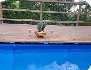 two glasses of wine on a table next to a pool at Chalet "Le Boisé" in Les Abymes