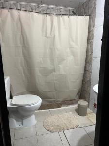 a bathroom with a toilet and a shower curtain at disfruta tu estadía in Salto