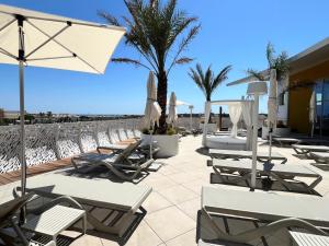 a row of lounge chairs and umbrellas on a beach at Le Royal VIBES in Cap d'Agde