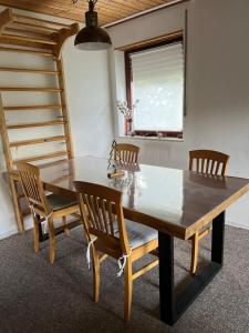 a dining room table with wooden chairs and a window at Ferienwohnung am Rande des Rothaarsteigs in Kreuztal