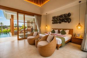 a bedroom with a large bed and two chairs at Arta Private Villa in Ubud