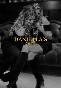 two women are sitting on a couch with drinks at Daniella's Suites in Peabody