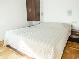 a white bed in a room with a wooden floor at Apartments Despot Zaostrog RR in Zaostrog