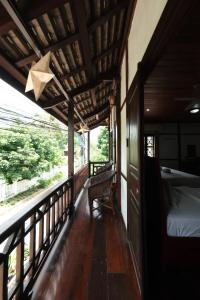a porch of a house with a bed and a balcony at KhounPhet Hotel in Luang Prabang