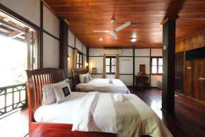 two beds in a room with wooden ceilings at KhounPhet Hotel in Luang Prabang