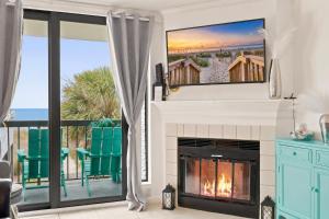 a living room with a fireplace with a tv above it at Beachfront Bliss 3BR Oceanfront Condo with Pool and Hot Tub in Myrtle Beach