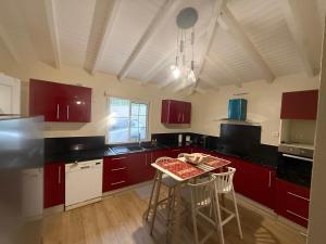 a kitchen with red cabinets and a table with chairs at Chez Francis in Petit-Bourg