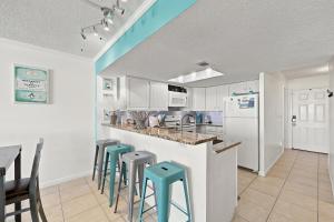 a kitchen with white cabinets and blue stools at Beachfront Bliss 3BR Oceanfront Condo with Pool and Hot Tub in Myrtle Beach +70 photos
