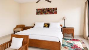 a bedroom with a large bed and a chair at Nakula Familiar Inn in Denpasar