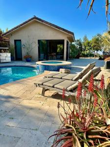 a swimming pool with lounge chairs next to a house at Hilltop View Sanctuary in Fallbrook
