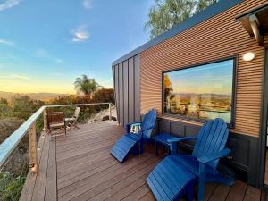 a deck with blue chairs and a table and a window at Hilltop View Sanctuary in Fallbrook