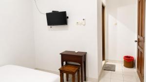 a bedroom with a bed and a table and a tv at Nakula Familiar Inn in Denpasar