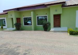 a green house with a brick driveway in front of it at Pizzaro Flats in Lusaka