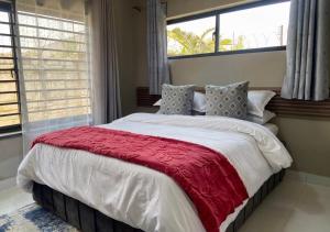 a bedroom with a large bed with a red blanket at Pizzaro Flats in Lusaka