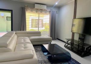 a living room with a white couch and a television at Pizzaro Flats in Lusaka